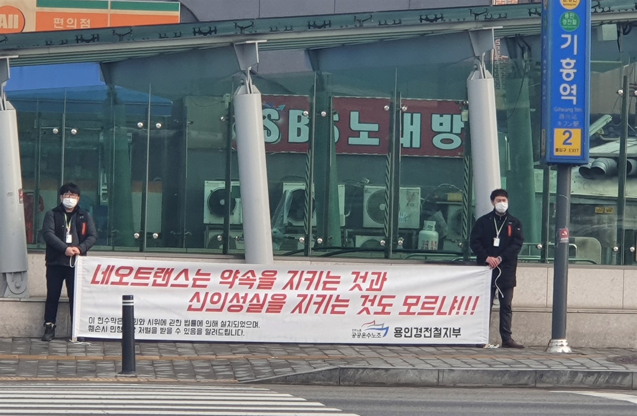 용인경전철 노조원들이 기흥역 앞에서 약식 현수막 시위를 벌이는 모습
