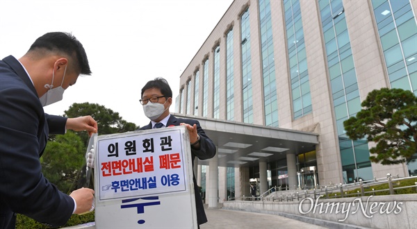 국회 직원들이 의원회관 전면안내실 폐쇄 안내문을 붙이고 있다.