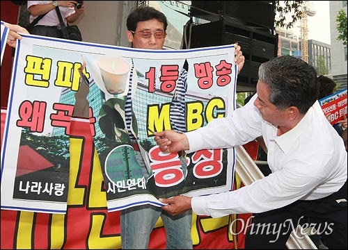 국민행동본부와 뉴라이트전국연합회원들이 2008년 6월 20일 오후 서울 여의도 MBC 본사 앞에서 '광우병선동방송 MBC 규탄' 집회에서 광우병 조작 보도하는 MBC 규탄의 현수막을 찢는 퍼포먼스를 하고 있다.