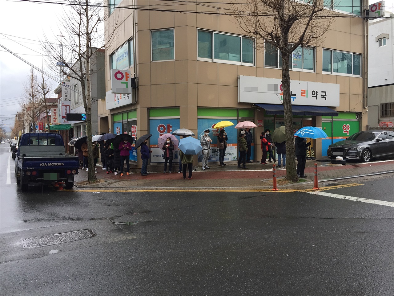 비가 오는 날씨인데도 마스크를 구매하기 위해 줄 서 기다리는 사람들의 모습