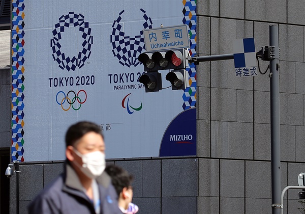 마스크를 쓴 남성이 9일 오후 도쿄 올림픽·패럴림픽 홍보물이 설치된 일본 도쿄도 치요다구의 한 사거리를 지나가고 있다.