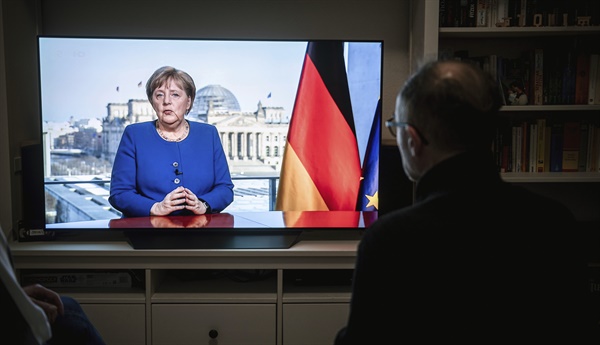 독일 오버하우젠의 한 주택 거실에서 18일(현지시간) 사람들이 TV를 통해 신종 코로나바이러스 감염증(코로나19) 확산 사태와 관련한 앙겔라 메르켈 총리의 대국민 연설을 듣고 있다. 