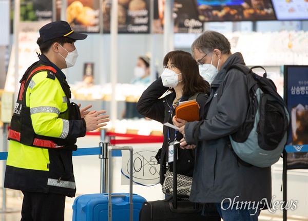  24일 오후 인천국제공항 제2여객터미널에서 '코로나19' 관련 지원나온 경찰이 입국 후 격리시설로 가기 위해 대기중인 외국인 승객들에게 관련내용을 안내하고 있다.