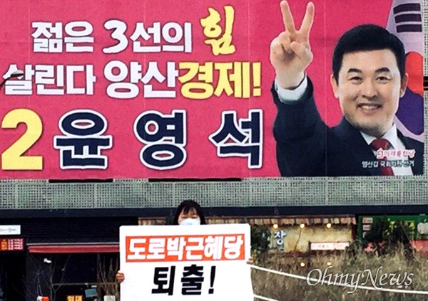 민중당 당원이 미래통합당 윤영석 의원 선거사무소 앞에 '도로 박근혜당 퇴출'이란 손팻말을 들고 서 있다.