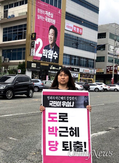 '사회대개혁, 총선승리 민중공동행동’ 회원이 미래통합당 박완수 후보 선거사무소 앞에서 손팻말을 들고 서 있다.