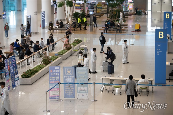 1일 오후 인천국제공항 제2여객터미널에서 각 지자체에서 나온 공무원들이 방역복을 입은 채 외국에서 입국한 승객들을 대상으로 '코로나19' 대비 안전한 귀가를 위한 교통편을 안내하고 있다. 1일부터 모든 해외입국자들은 2주간 자가격리를 해야하며, 위반시 정부는 무관용원칙으로 처벌할 것이라 밝혔다.