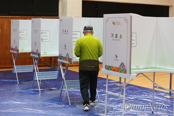 21대 총선 투표일인 2020년 4월 15일 서울 강북구 번동초등학교에 마련된 투표소에서 한 유권자가 투표용지를 들고 기표소로 들어가고 있다.
