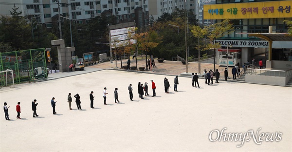 21대 총선 투표일인 15일 오전 서울 성북구 숭인초등학교에서 '코로나19' 감염예방을 위해 마스크를 쓴 유권자들이 투표를 하기 위해 운동장에 길게 줄을 서 있다.