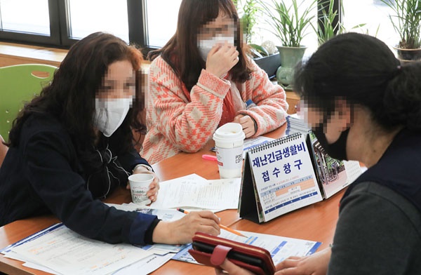 서울시내 한 주민센터에서 직원들이 주민에게 긴급생활비 신청 여부에 대한 안내를 해주고 있다. 