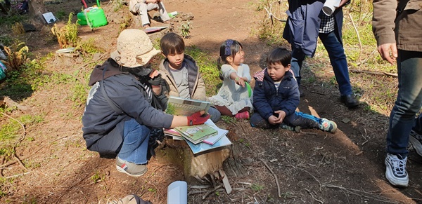 이날 행사에 참여한 여러 어린이들을 대상으로 나무 그루터기 주변에 둘러 않은 어린이들에게 책을 읽으며 나무의 소중함 등을 일께우고 있다.