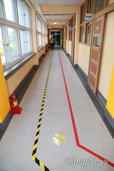 학교 현관에는 등교하는 학생들이 교실로 가기 전 발열체크를 하기 위해 이동하는 통로가 설치되어 있다. 일정한 거리를 유지하기 위해 발자국 스티커가 바닥에 붙어 있다.