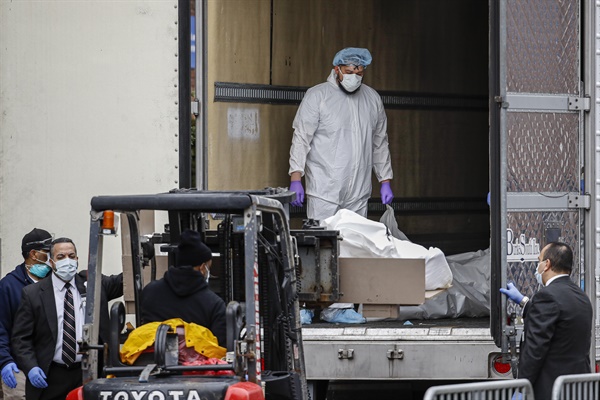 31일(현지시간) 미국 뉴욕 브루클린에 있는 한 병원에서 방호복을 입은 의료진이 비닐로 싸인 신종 코로나바이러스 감염증(코로나19) 사망자 시신을 임시영안실로 사용되는 냉동트럭에 싣고 있다.
