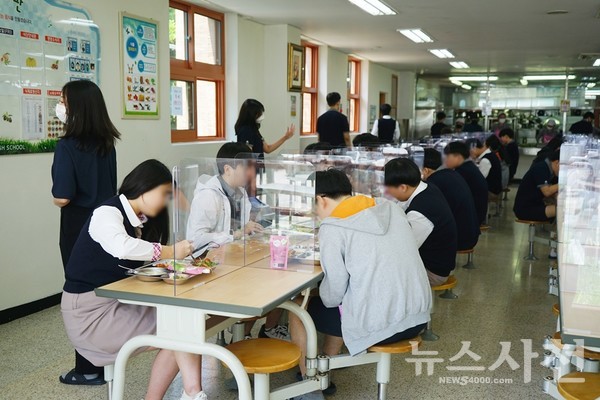  5월 20일 사천 용남고등학교 급식소에서 학생들이 투명 칸막이가 설치된 식탁에 지그재그로 앉아 점심식사를 하고 있다.