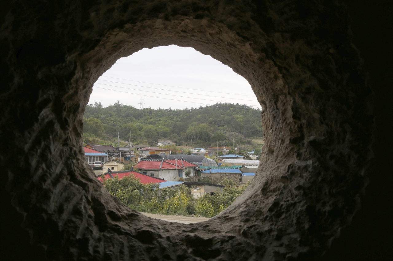 맷돌의 밑바닥을 깎아서 둥근 창틀로 만든 창, 그 둥근 창으로 마을이 보인다. 전라남도 신안군 증도면 대기점도 북촌마을에 있는 안드레아의 집이다.