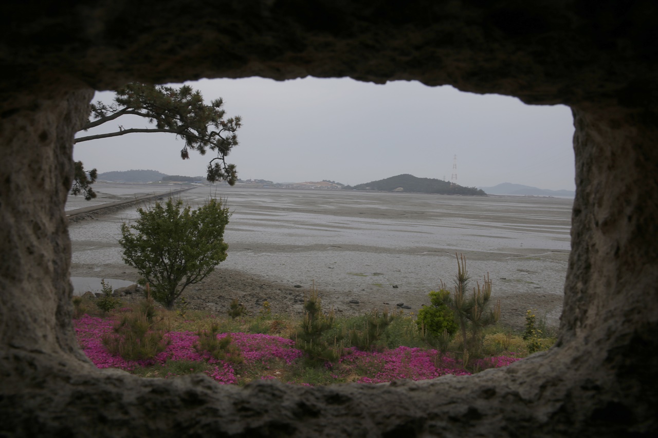 직사각의 창으로 노두와 바다 건너편의 섬이 보인다. 돼지의 먹이를 담아주는 콘크리트 구유를 깎아서 창틀로 만들었다. 신안군 증도면 대기점도의 안드레아의 집 풍경이다.