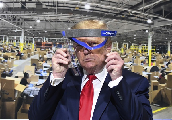 도널드 트럼프 미국 대통령이 21일(현지시각) 미시간주의 포드 자동차 로슨빌 부품공장을 시찰하며 얼굴 가리개를 들어보고 있다.