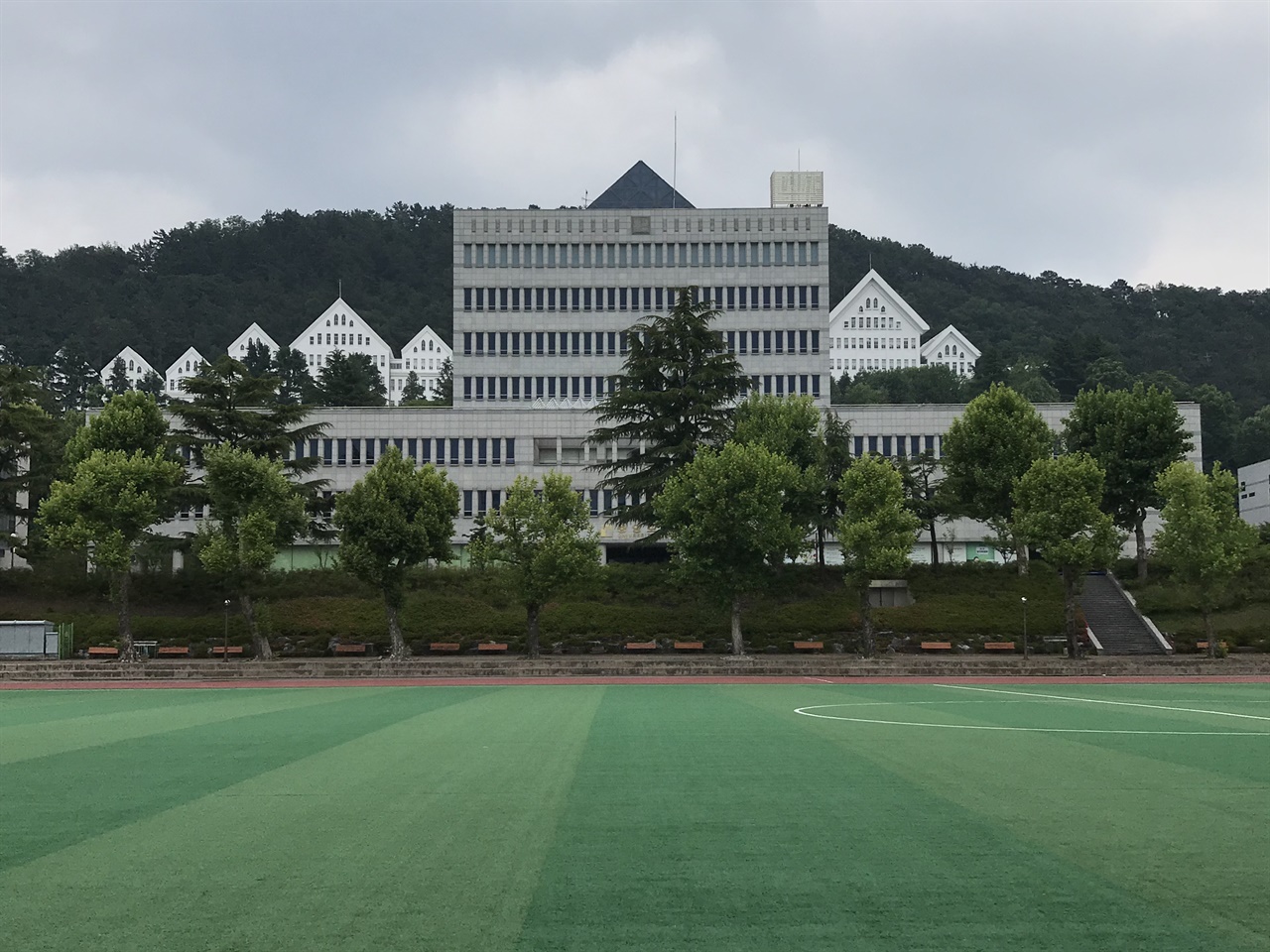 조선대학교 대운동장과 중앙도서관 5.18 당시 조선대학교 대운동장은 7공수여단이 주둔했던 공간이다. 5월 19일부터 21일 사이에 계엄군에 끌려온 시민과 학생이 조선대 체육관에서 고문과 폭행을 당하기도 했다. 대운동장 뒤로 보이는 건물은 2003년 개관한 조선대학교 중앙도서관이다. 중앙도서관 뒤로 보이는 건물이 조선대학교 본관이다. 한때 본관 일부 공간이 ‘도서관’으로 쓰였다. 조선대학교 본관은 이길성이 설계했고, 1948년 건립한 박공지붕의 조적조 6층 건물이다. 