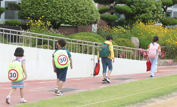  고등학교 1학년·중학교 2학년·초등학교 3∼4학년을 대상으로 한 3차 등교 개학일인 3일 오전 경남 김해시 삼성초등학교 입구에서 학생들이 바닥에 붙은 '간격' 표시 테이프 길을 따라 등교하고 있다.