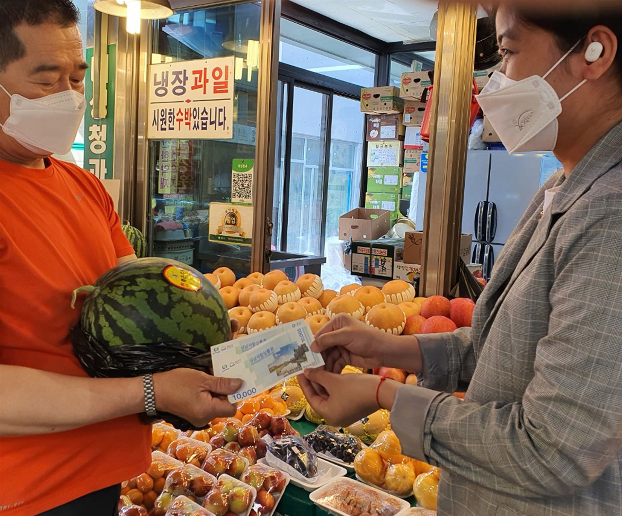  캄보디아 출신 결혼이민자가 성남 중앙시장에서 성남사랑상품권으로 수박을 사고 있다