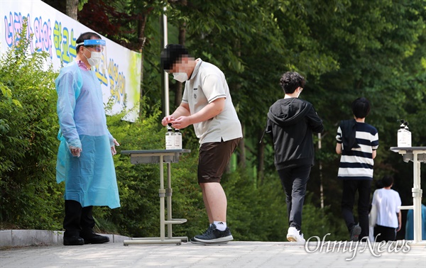 고3학생이 코로나19 확진을 받은 서울 중랑구 원묵고등학교에서 8일 오전 학생, 교직원 600명을 대상으로 교내에 설치된 선별진료소에서 전수조사가 실시되고 있다. 학생들이 교직원의 안내를 받으며 손소독을 한 뒤 교문을 들어가고 있다.