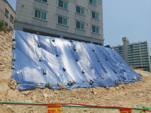 울산 동구 남목원룸을 지탱하다 깎여 나간 경사진 언덕에 동구청이 물이 스며드는 것을 막기 위해 방수포를 덮어놓았다.