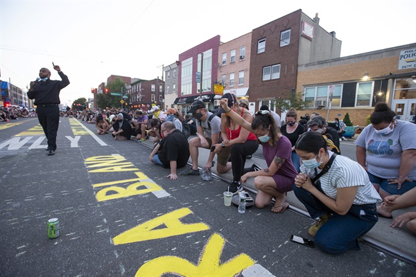 2020년 6월 10일, 미국 필라델피아 한 도로 위에 시민들이 '이제 인종차별 끝장내자'는 구호와 함께 에밋 틸ㆍ조지 플로이드 등 인종차별 희생자들의 이름을 적고 그 앞에서 고개 숙여 기도하고있다.
