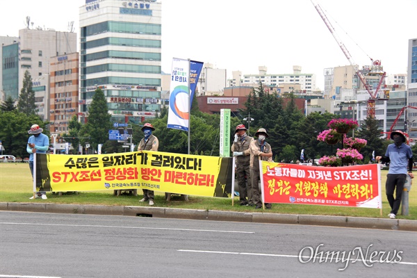 전국금속노동조합 STX조선지회 조합원들은 6월 17일 창원시청 앞 광장에서 갖가지 구호를 새진 펼침막을 들고 서 있다.