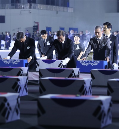 문재인 대통령이 25일 서울공항에서 열린 6·25전쟁 70주년 행사에서 국군 전사자들의 유해에 참전기장을 수여한 뒤 묵념하고 있다.