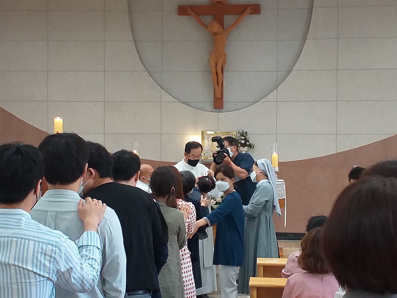 예비신자와 그의 대부 대모님들이 신부님의 영세수 축복을 기다리며 서 있다. 죄의 씻김과 구원의 상징이라고 한다 