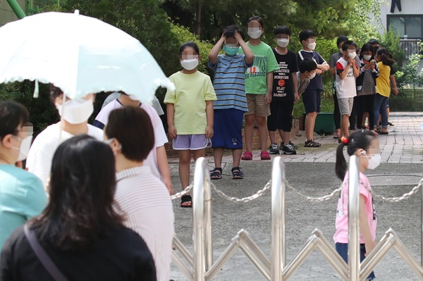 5일 서울 중랑구 묵현초등학교에 마련된 임시 선별진료소에서 학생들이 검사를 받기 위해 길게 줄지어 서 있다. 서울 중랑구는 묵현초 학생 1명이 신종 코로나바이러스 감염증(코로나19) 확진 판정을 받았다고 전날 밝혔다.