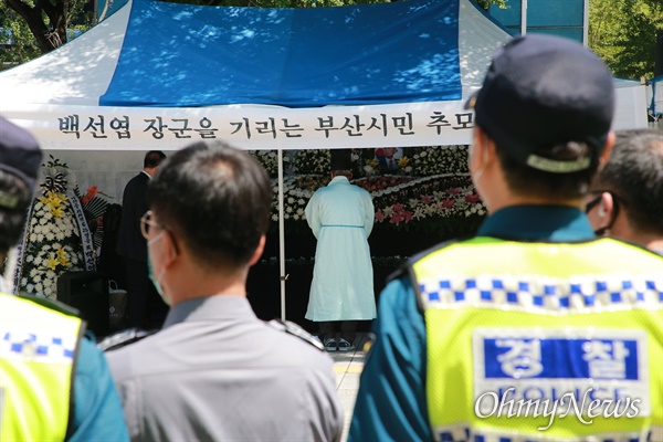  부산시청 광장에 마련된 고 백선엽 장군 부산시민 추모분향소를 둘러싸고 16일 진보단체가 규탄 기자회견에 나서자 경찰이 배치됐다. '경찰벽' 뒤로 추모행렬이 이어지고 있다.