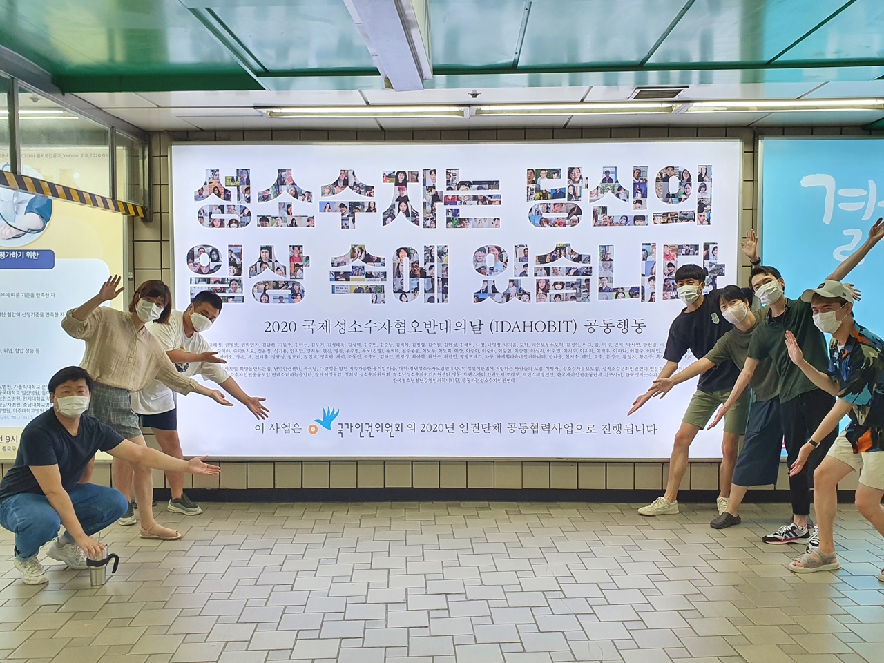 광고 앞에서 인증활동을 하는 무지개행동 활동가들