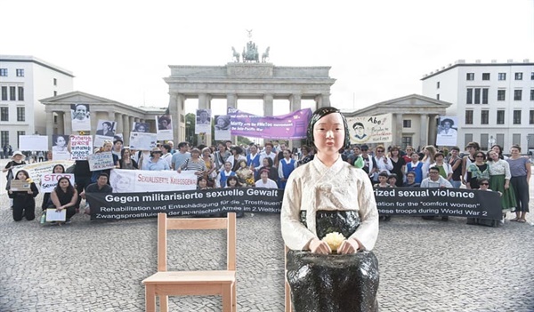 작년 8월 14일 세계 일본군 위안부 기림일, 브란덴부르크 문 앞에서 열린 시위. 베를린의 여러 여성단체들과 "용희" 라는 이름의 소녀상도 집회에 함께 했다. 