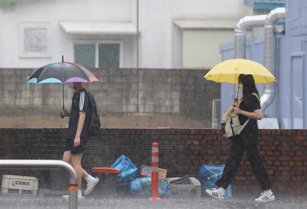 중학교 학생들이 세차게 내리는 비를 맞으며 등교하고 있다.
