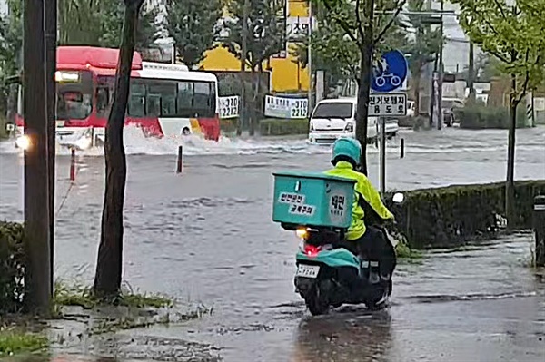 7일 광주 지역에 내린 폭우로 인해 곳곳이 침수된 모습. 광주 서구 동천동의 한 도로를 배달라이더가 위태롭게 지나고 있다. 