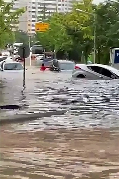7일 광주 지역에 내린 폭우로 인해 곳곳이 침수된 모습. 광주 북구 문흥동의 도로에서 한 시민이 물에 잠긴 차 문을 열려고 시도하고 있다. 