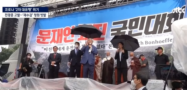 전광훈 목사가 '광화문 집회'에서 마스크를 안 쓰고 연설하는 모습을 JTBC가 보도했다. 연단에 다른 사람들도 많다.