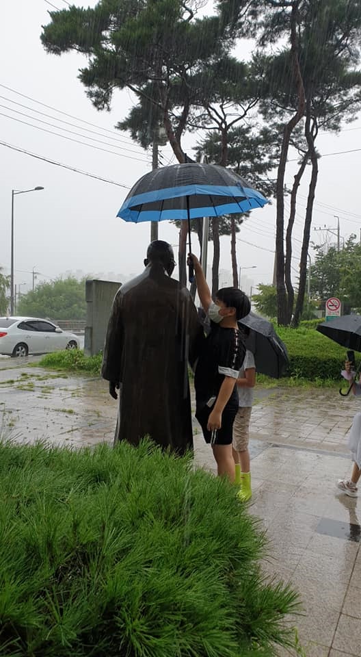 비맞는 김구선생 동상에 우산을 씌우는 학생