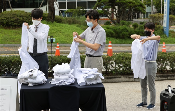  8월 23일 오전 서울 종로구 서울대병원 대학의원 본관 앞에서 정부의 의료정책에 반대하는 전공의들이 의사 가운을 탈의하고 있다.