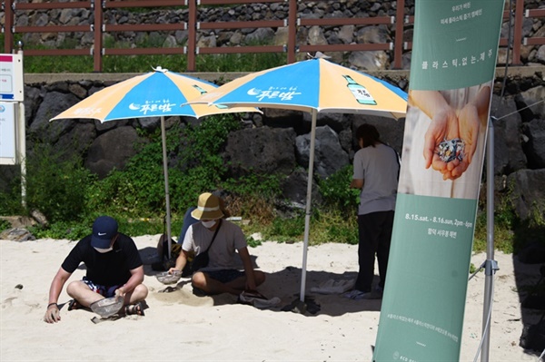 시민들이 모래 해변에서 미세 플라스틱을 줍고 있다. 