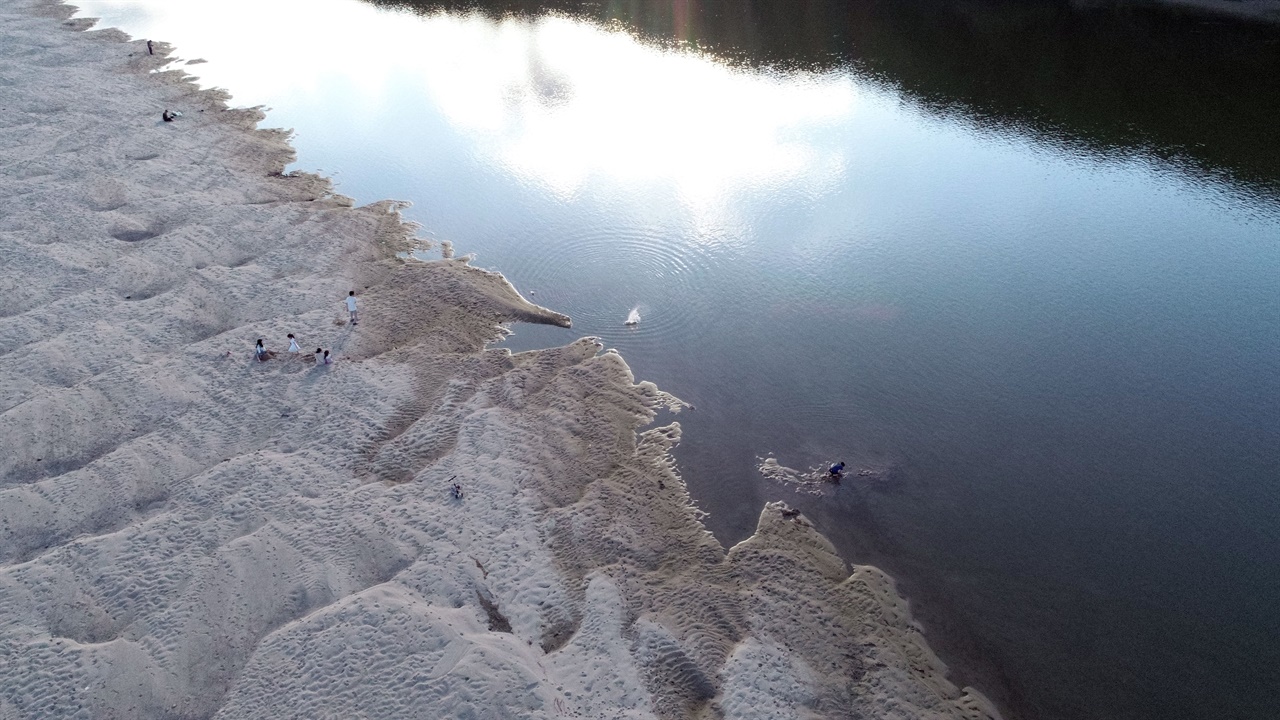  강변 모래톱에는 많은 시민이 찾아 휴식을 취하고 아이들은 모래 장난에 여념이 없습니다. 