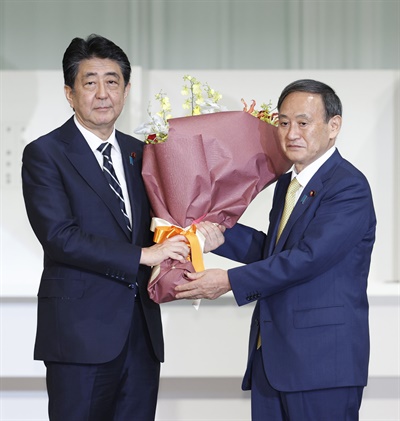 지난 14일 일본 자민당 총재 경선이 끝난 뒤 아베 신조(安倍晋三) 총리로부터 축하 꽃다발을 받는 스가 신임 자민당 총재. 