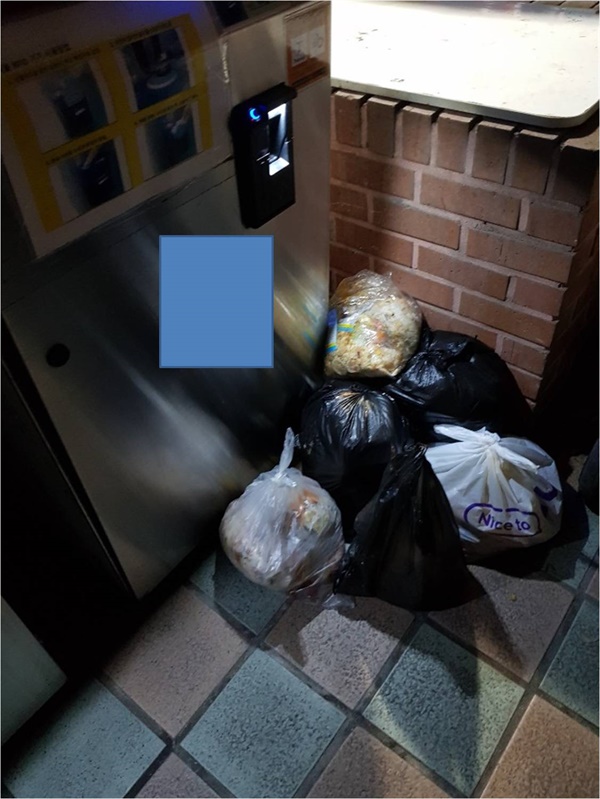 음식물 쓰레기통 앞에 버려진 음식물 쓰레기 봉투