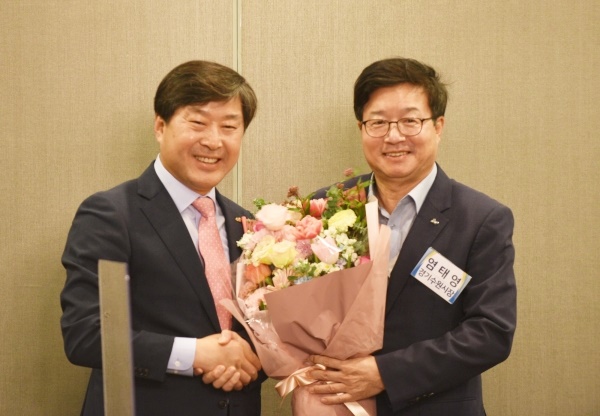  이임 황명선 회장(논산시장)이 신임 염태영(수원시장)회장에게 축하 꽃다발을 전달하고 있다