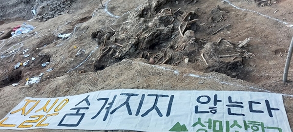 성미산학교 학생 12명이 대전 골령골에서 유해발굴 봉사활동을 마친 후 희생자 유해 앞에 '진실은 숨겨지지 않는다'는 천 글씨를 펼쳤다.