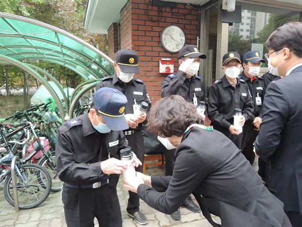  대전충남녹색연합 김은정 대표가 경비노동자에게 커피가 담긴 텀블러를 선물하고 있다