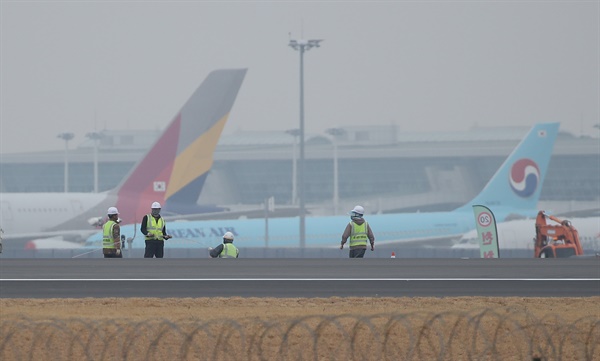 대한항공의 아시아나항공 인수 발표가 하루 지난 17일 오후 인천국제공항 제4활주로 공사현장 뒤로 대한항공과 아시아나항공 여객기들이 세워져 있다.