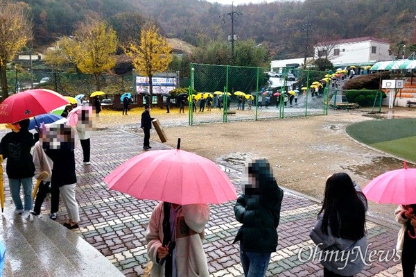 비가 내리는 가운데 19일 창원진해 한 학교에 마련된 선별진료소에서 많은 사람들이 코로나19 진단검사를 받고 있다.