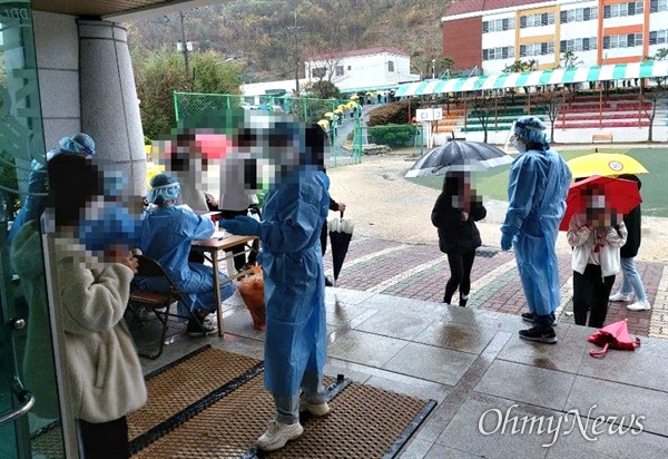 비가 내리는 속에 11월 19일 창원진해 한 학교에 마련된 선별진료소에서 많은 사람들이 코로나19 진단검사를 받고 있다.