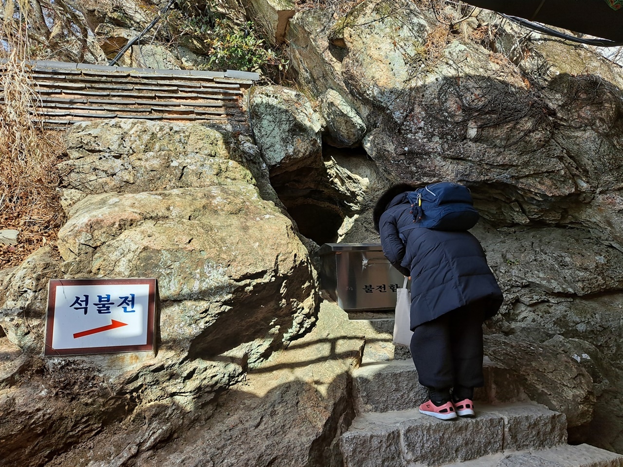  석불 앞에서 한 여인이 소원을 빌고 있다.
